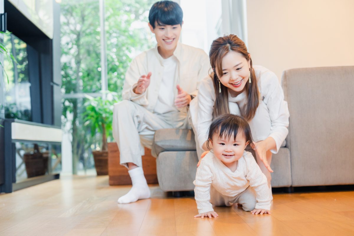 ハイハイする赤ちゃんを見守る両親