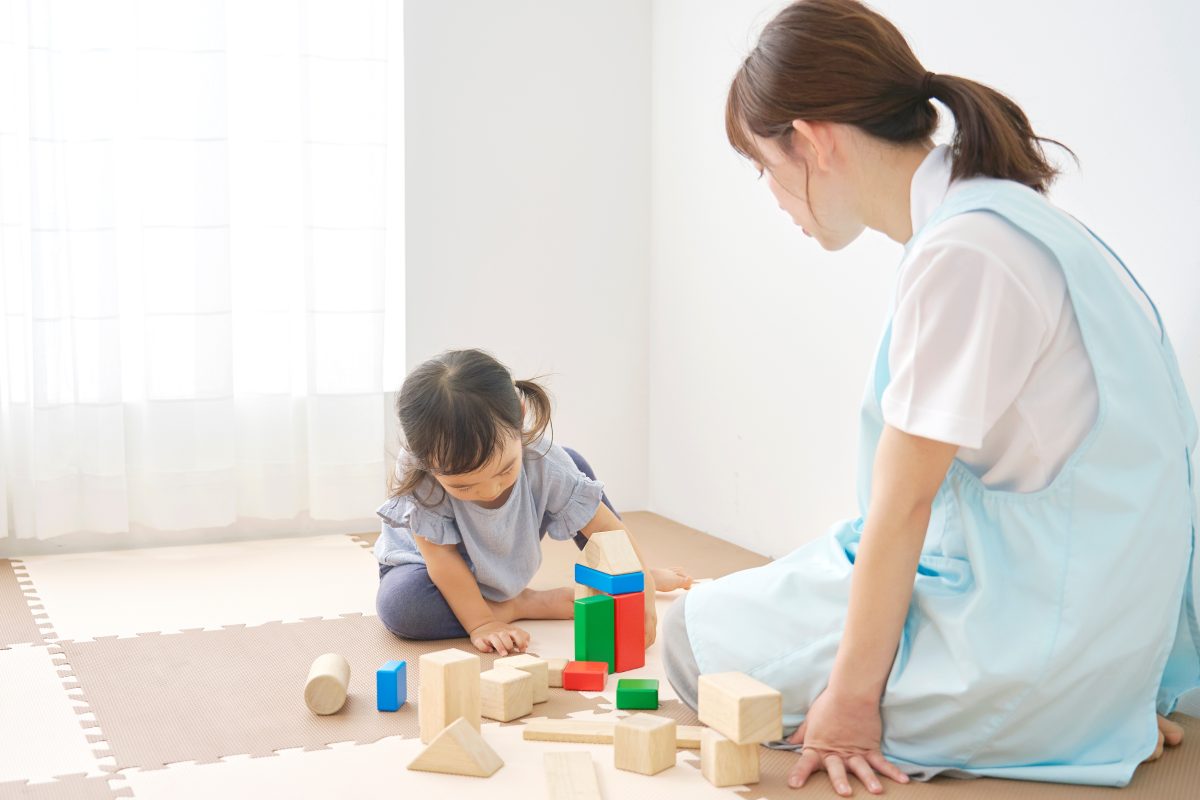 積み木で遊ぶ子どもを見守る専門職